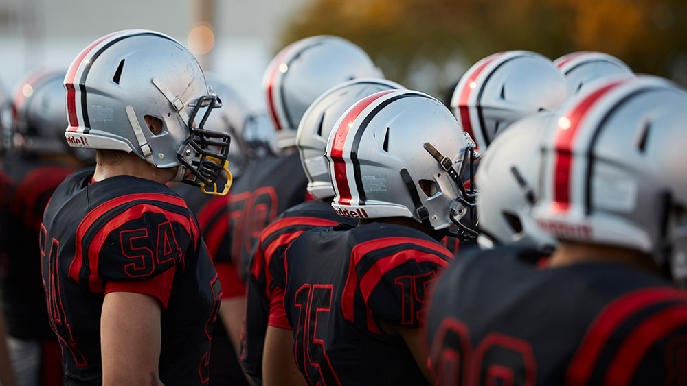 football players wearing red and black athletic uniforms and helmets